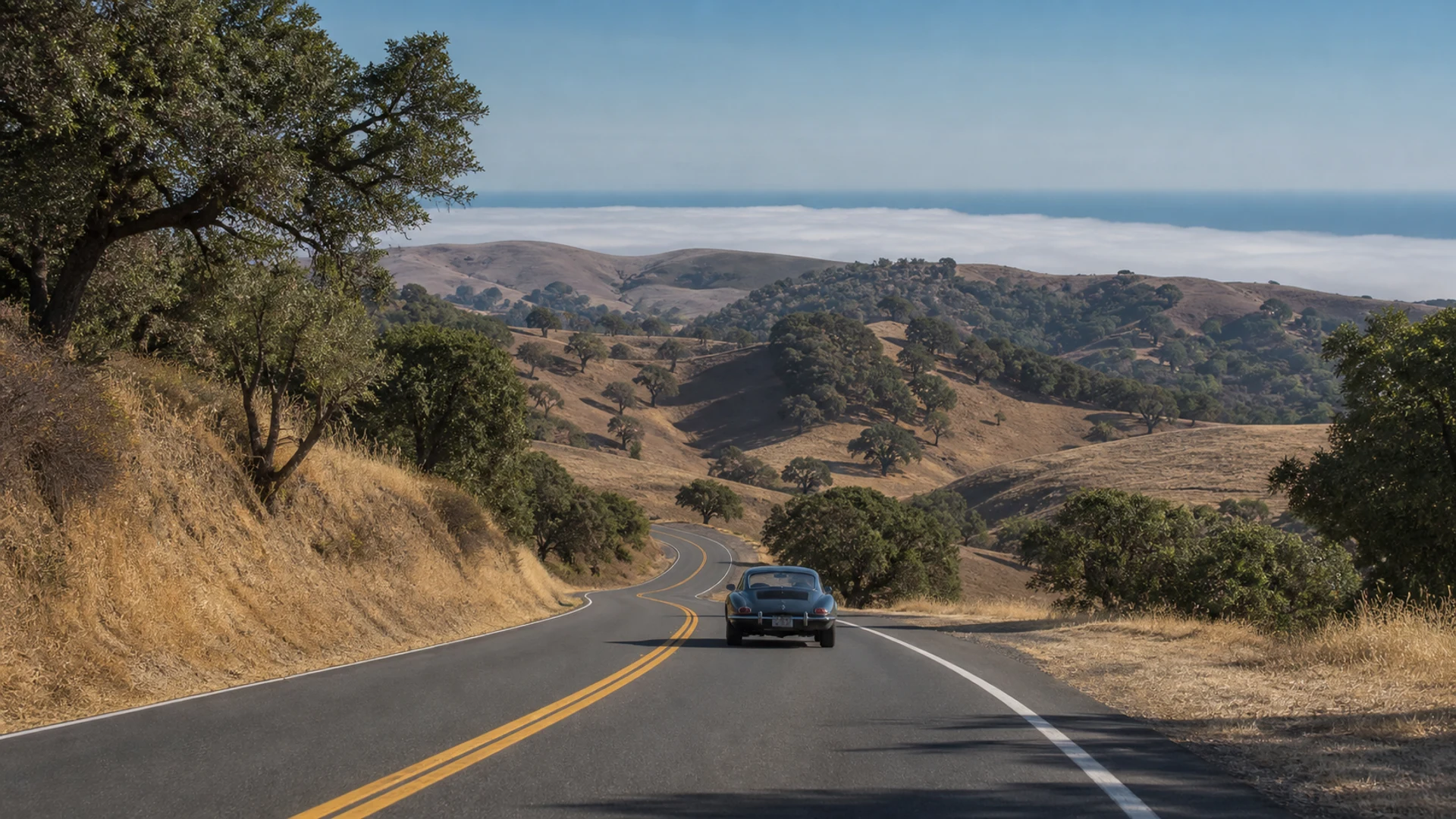 A classic coupe descending a California road toward the coast