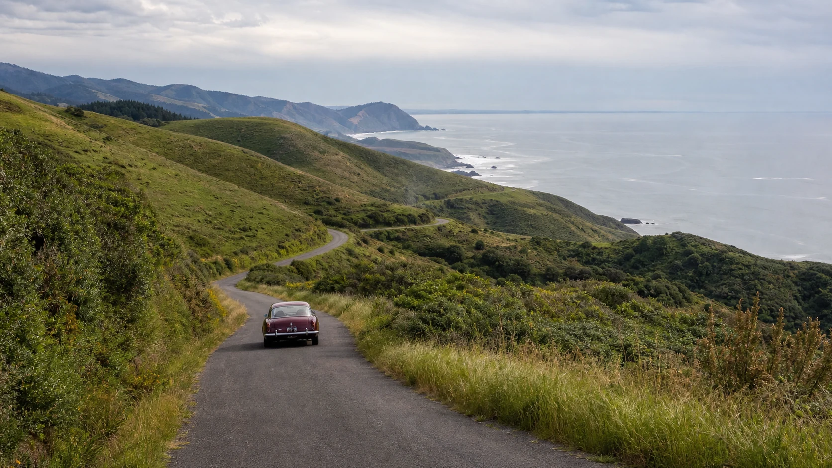 A classic sports car following a winding road above the Lost Coast